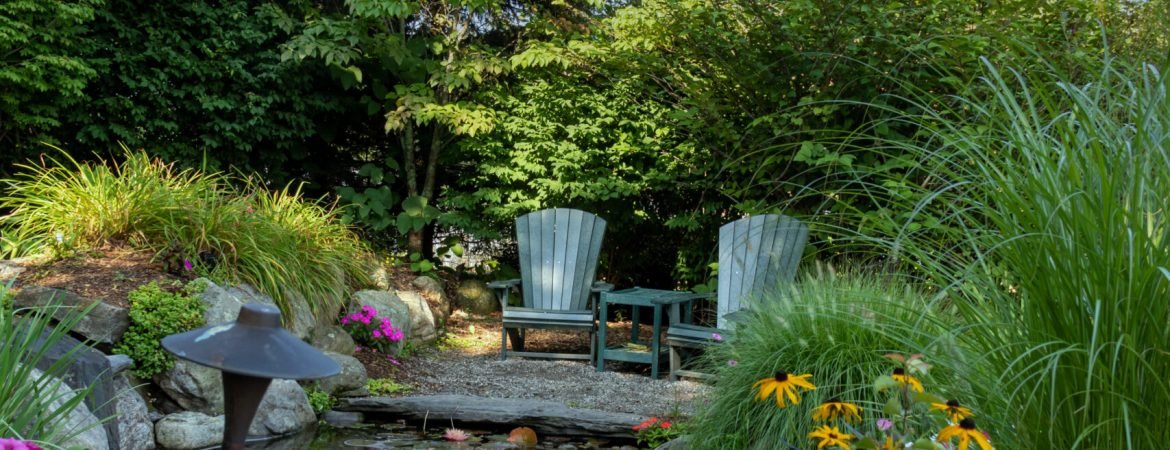 Landscape architecture with pink flowers and ornamental grasses for summer garden with water feature